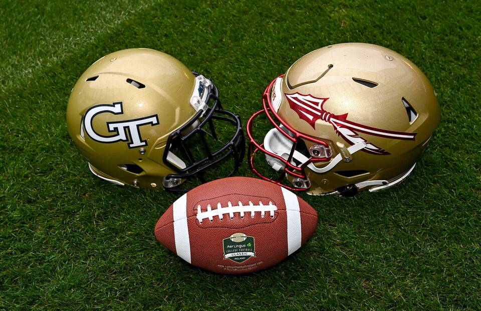 Aer Lingus College Football Classic teams helmets on the green pitch beside an american football